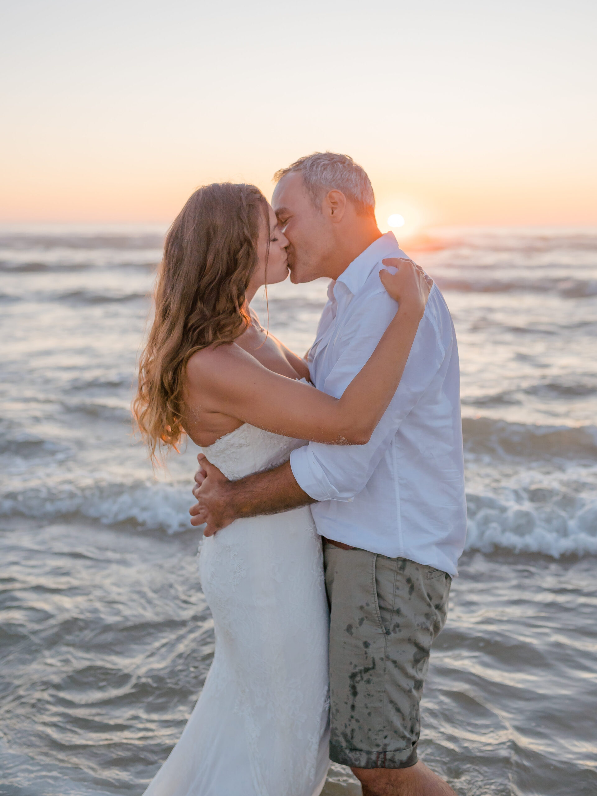 Ein Brautpaar küsst sich beim Sonnenuntergang am Strand in Portugal.