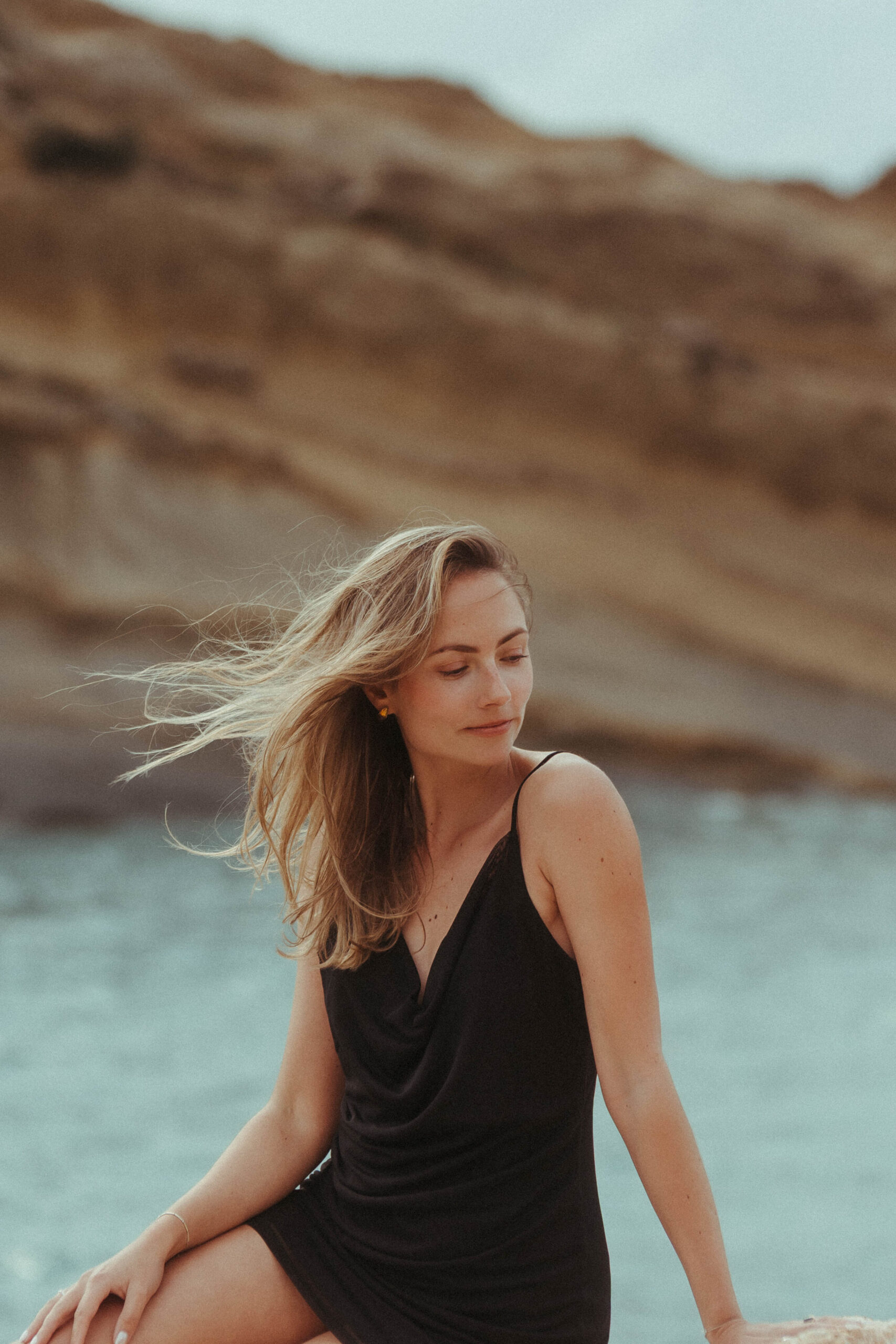 Die Fotografin Jasmin von Kulleraugen-Fotografie sitzt auf einem Stein am Meer. Hochzeitsfotografin Karlsruhe.